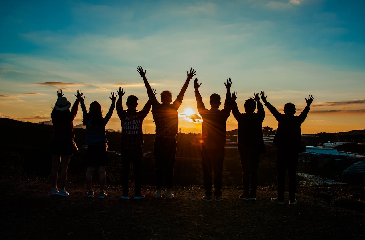 brand-02 A diverse group of friends raises their arms in celebration against a vibrant sunset backdrop.